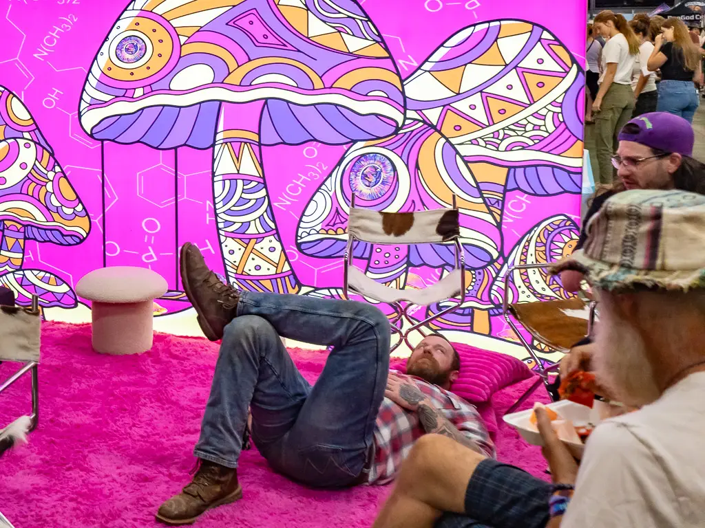 a hot pink mushroom themes seating lounge with some festival attendees taking a break to recharge.