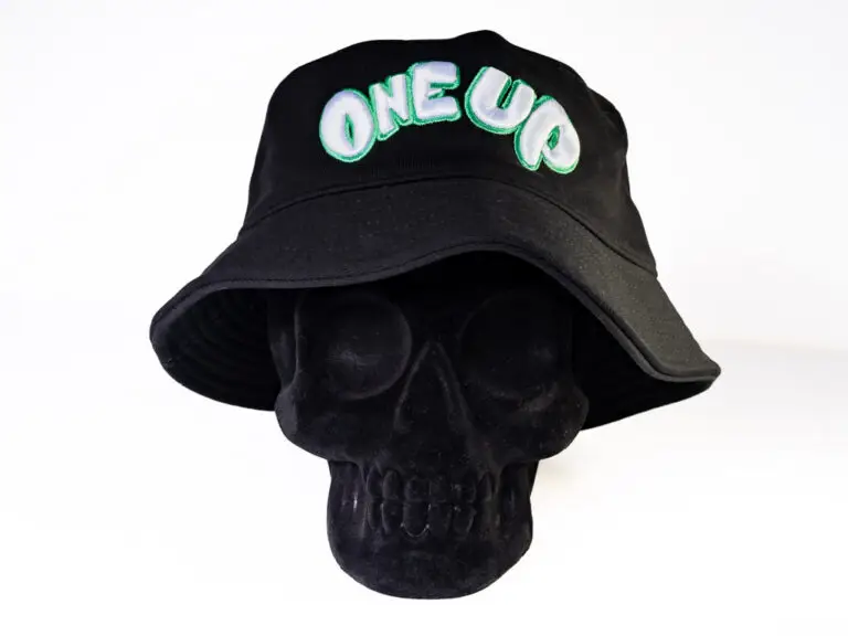 Black bucket hat with green and white classic One Up logo embroidered across the front side.