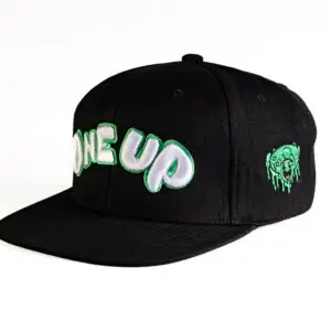 Black snapback ball cap with an embroidered green and white one up logo on the front , and a green mushroom smiley face on the side.