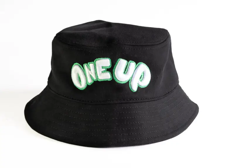 Black bucket hat with green and white classic One Up logo embroidered across the front side.